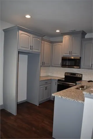 a kitchen with granite countertop white cabinets and wooden floor
