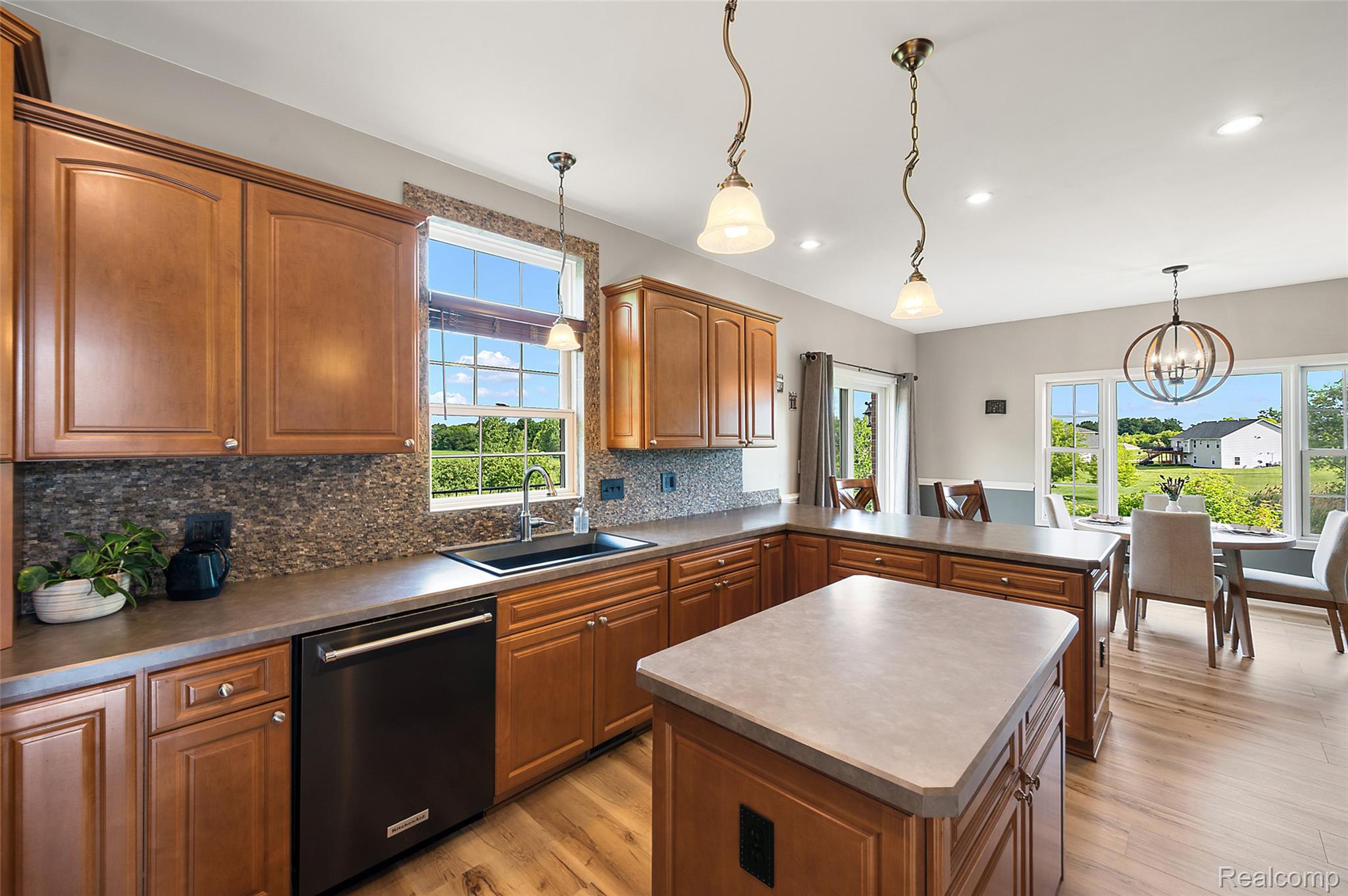 5035 Hidden Ridge Road Metamora, MI 48455 - Photo 18 of 65 Open-concept kitchen featuring wood-finish flooring, warm tone cabinetry, a dark tone countertop, and a mosaic tile backsplash