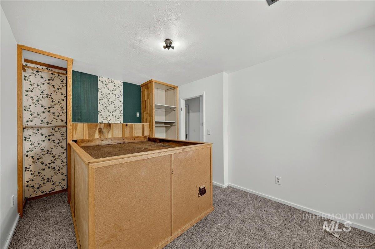 2160 South Five Mile Road Boise, ID 83709 - Photo 25 of 41 Carpeted room featuring a built-in wooden structure, an open closet with floral wallpaper, and integrated shelving units
