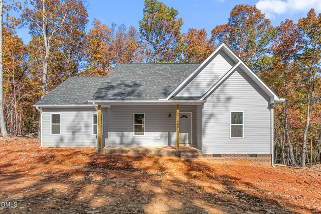 a front view of house with yard and trees in the background