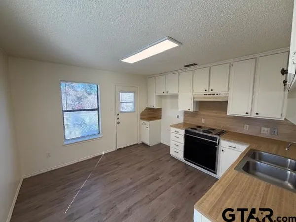 a kitchen with granite countertop a stove top oven and cabinets