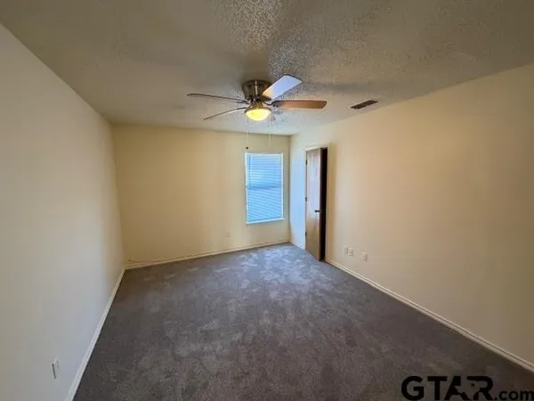 an empty room with a ceiling fan and a window