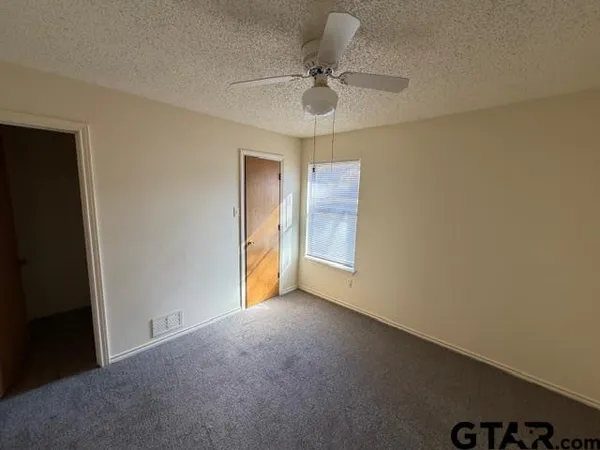 a view of an empty room and chandelier fan