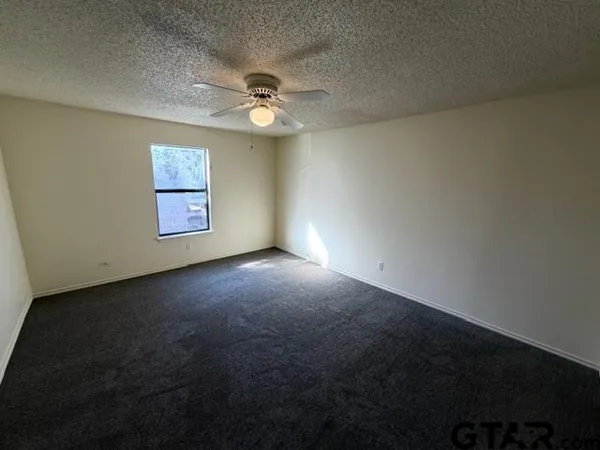 en empty room with windows and ceiling fan