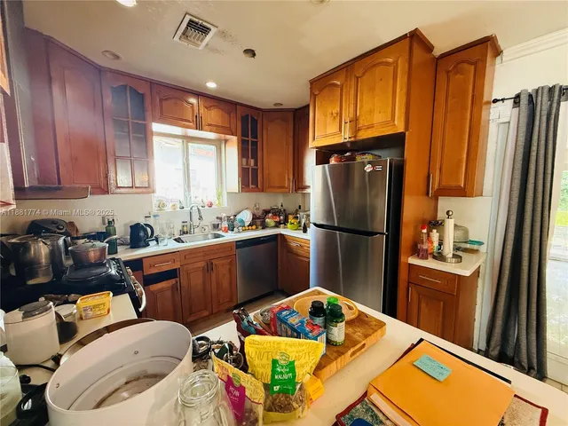 a kitchen with stainless steel appliances granite countertop a refrigerator a sink dishwasher and wooden cabinets