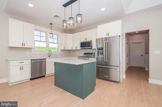 a kitchen with a sink a counter top space stainless steel appliances cabinets and a window