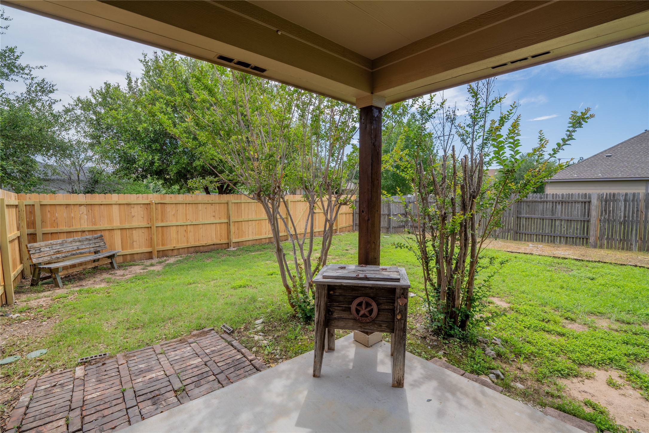 403 Tascate Street Georgetown, TX 78628 - Photo 23 of 26 A spacious backyard with mature trees, a sturdy wooden fence, and a inviting covered patio.