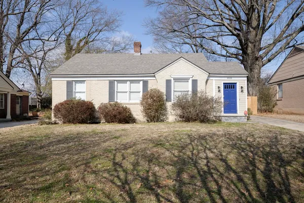 a front view of house with yard and trees around