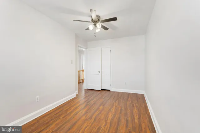 an empty room with wooden floor and a ceiling fan