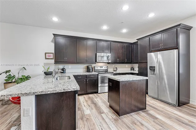 a kitchen with granite countertop a sink stove and refrigerator