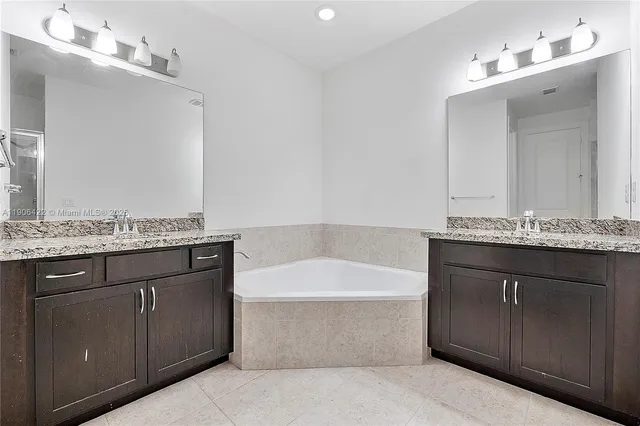 a bathroom with a granite countertop bathtub a sink and a mirror