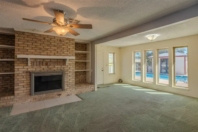 a view of an empty room with a fireplace and a window