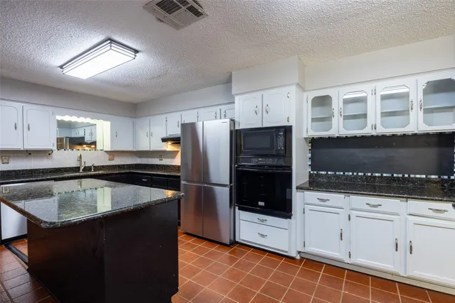 a kitchen with granite countertop a sink stove and refrigerator
