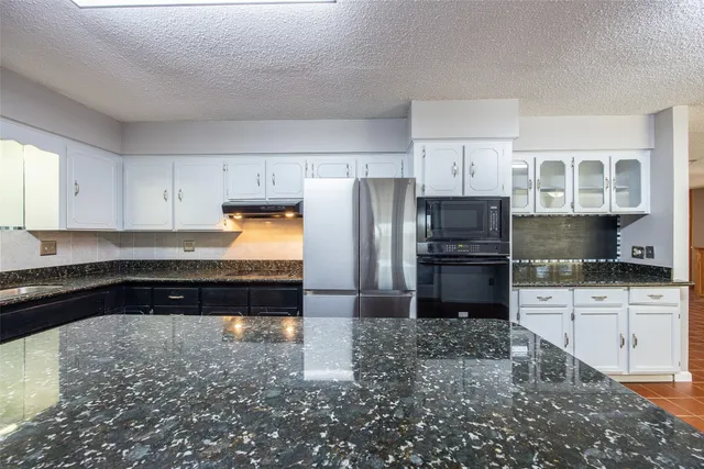 a kitchen with granite countertop a refrigerator a stove a sink and dishwasher