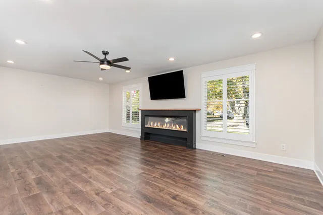 a view of a livingroom with a fireplace a window and wooden floor