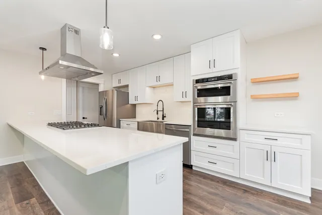 a kitchen with stainless steel appliances a stove a microwave and white cabinets