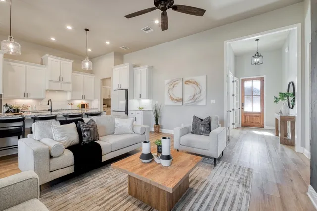 a living room with furniture kitchen view and a wooden floor