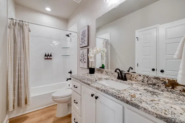 a bathroom with a granite countertop sink toilet and shower