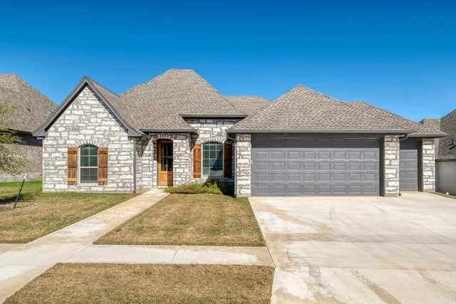 a front view of a house with a garden and yard