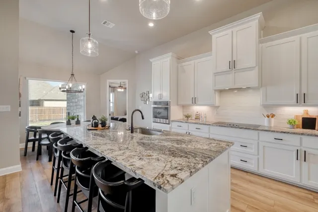 a kitchen with kitchen island granite countertop a table chairs sink and cabinets