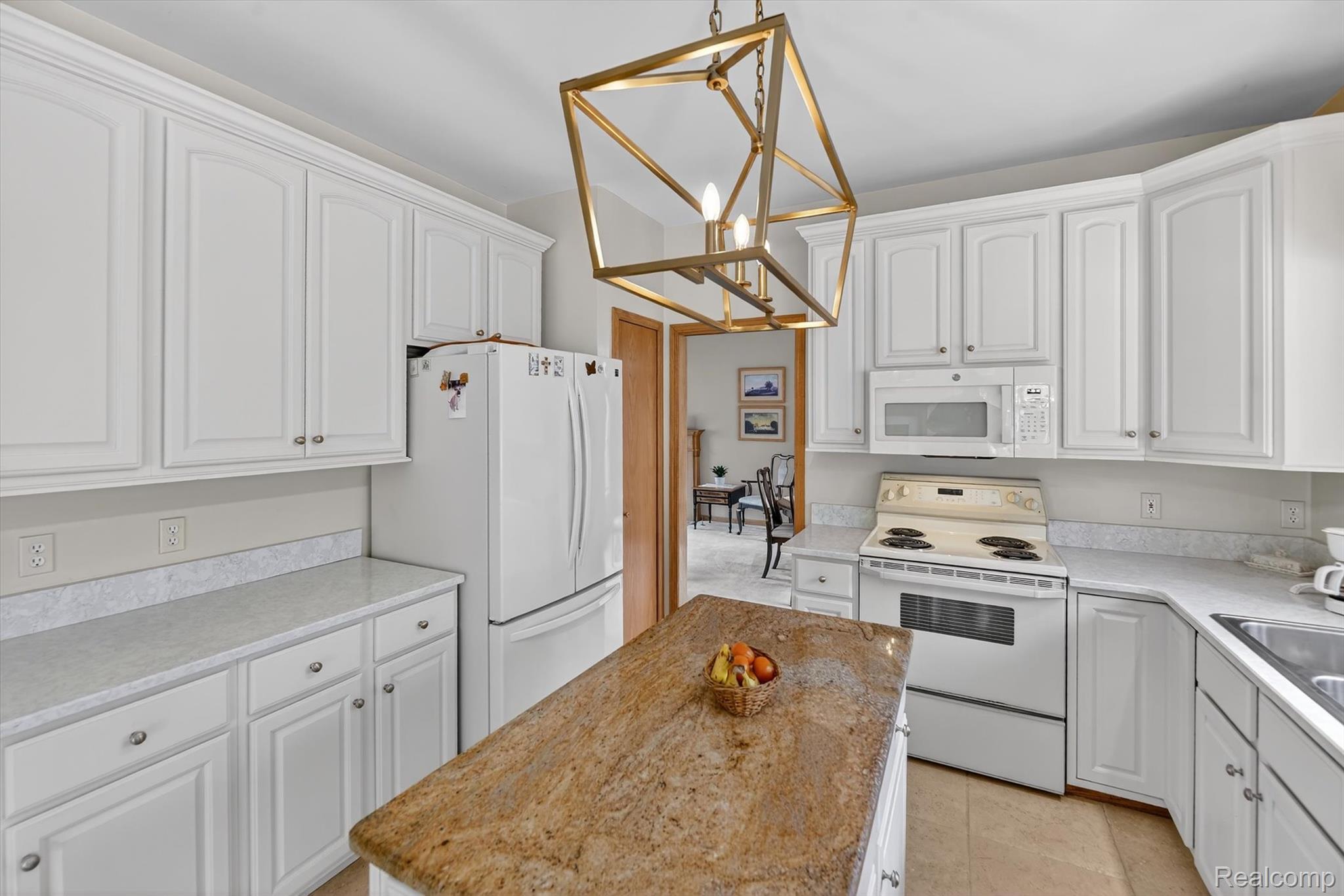 7798 Lee Road Brighton, MI 48116 - Photo 12 of 49 Kitchen featuring white appliances, white cabinets, light countertops, and a center island