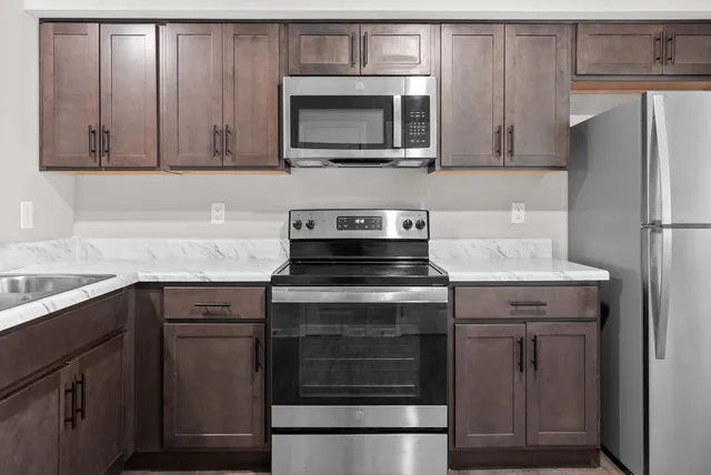 a kitchen with granite countertop white cabinets and stainless steel appliances