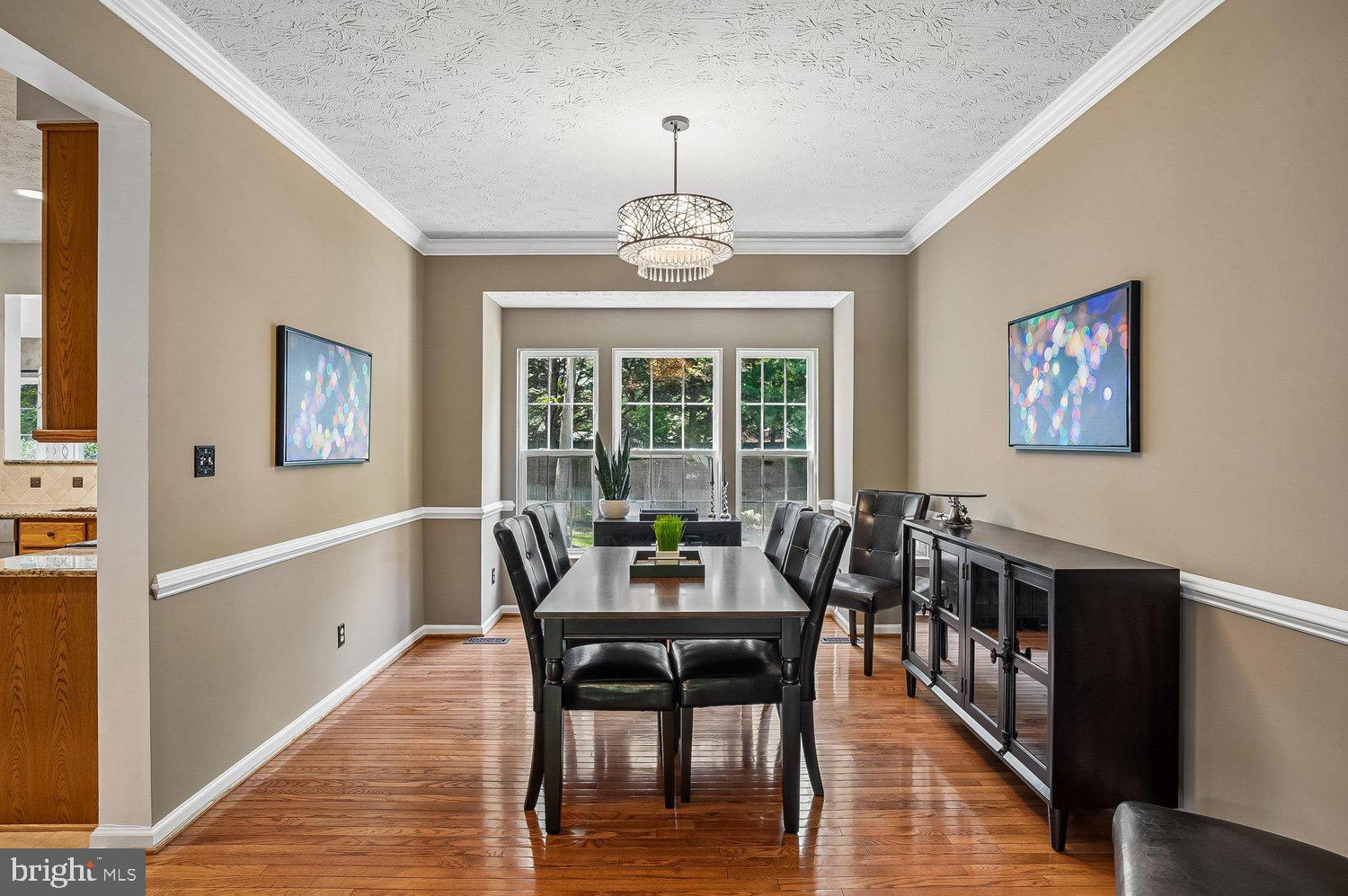 217 Raccoon Run Court Hanover, MD 21076 - Photo 5 of 38 a dining room with wooden floor a chandelier a wooden table and chairs