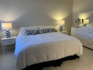 1605 Highway 1, Unit F204 Jupiter, FL 33477 - Photo 13 of 33 a bed sitting in a bedroom next to a lamp