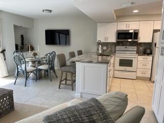 1605 Highway 1, Unit F204 Jupiter, FL 33477 - Photo 6 of 33 a living room with stainless steel appliances a stove a sink a microwave a dining table and chairs