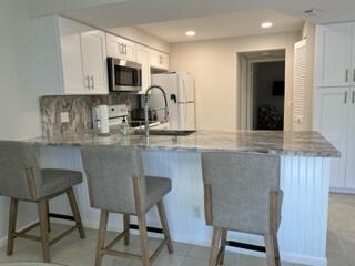 1605 Highway 1, Unit F204 Jupiter, FL 33477 - Photo 7 of 33 a kitchen with kitchen island granite countertop a table chairs microwave and sink