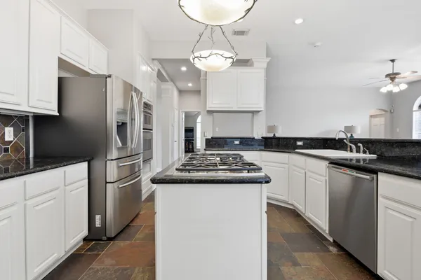 a kitchen with stainless steel appliances granite countertop a sink a stove a refrigerator and cabinets