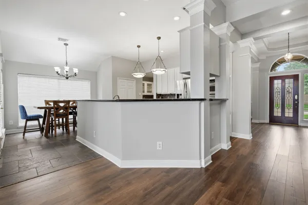 an open kitchen with wooden floor and stainless steel appliances