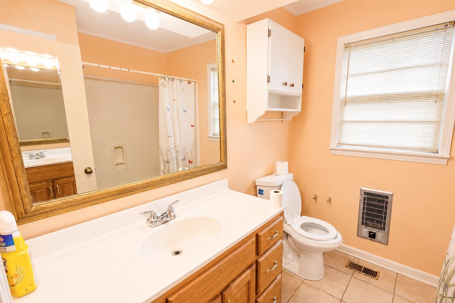2000 Culbreath Road Covington, TN 38019 - Photo 12 of 16 Bathroom featuring a vanity with a white countertop and wood-finish cabinetry, a framed mirror with vanity lighting, a toilet, a window with blinds, and built-in wall cabinetry