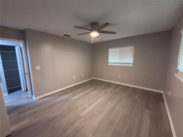 an empty room with wooden floor closet and windows