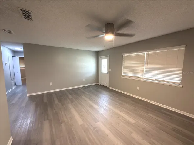 a view of an empty room with wooden floor and a window