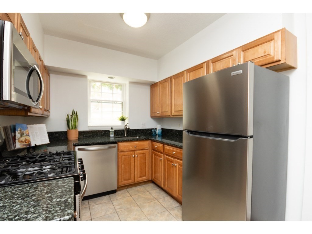 132 Lake Shore Road, Unit 1 Boston, MA 02135 - Photo 7 of 31 a kitchen with stainless steel appliances granite countertop a refrigerator a sink a stove and white cabinets