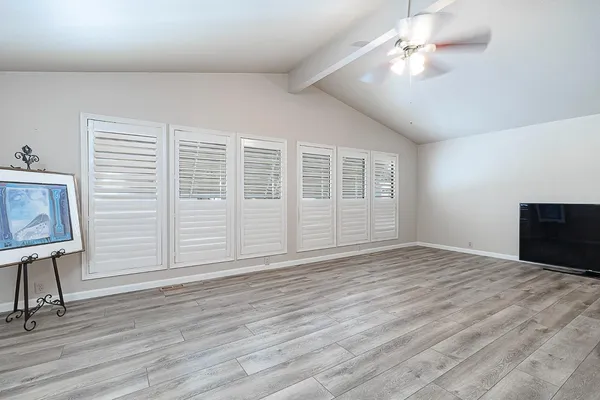 a view of empty room with wooden floor and fan