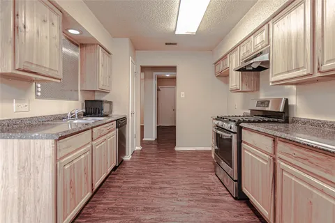a kitchen with stainless steel appliances granite countertop a stove a sink and a refrigerator