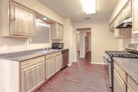 a kitchen with granite countertop a sink stove and cabinets