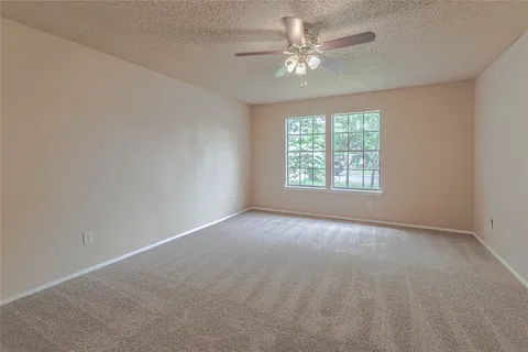 an empty room with a chandelier fan and windows