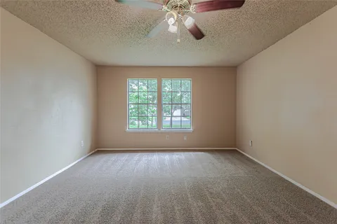 an empty room with a chandelier fan and windows