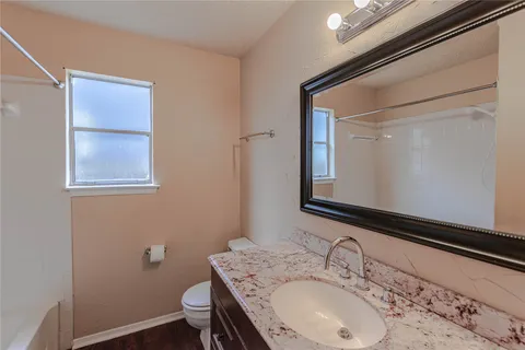 a bathroom with a granite countertop sink a toilet and a mirror