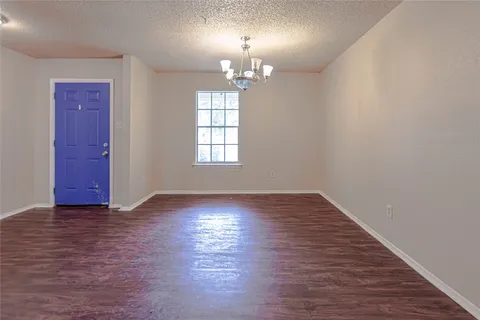 an empty room with wooden floor chandelier and windows