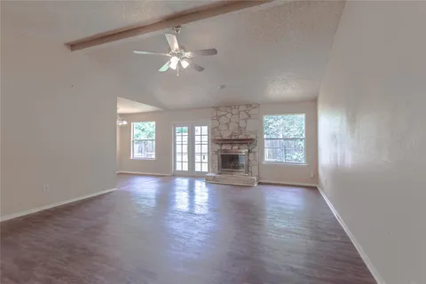 an empty room with wooden floor chandelier and windows