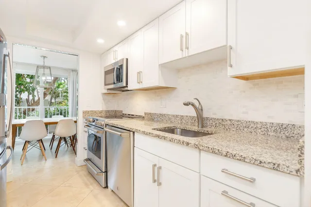 a kitchen with granite countertop a sink stainless steel appliances and cabinets