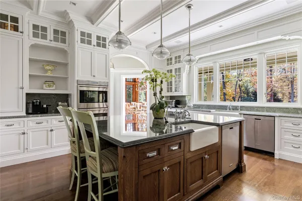 a dining room with wooden floor a chandelier a glass table and chairs