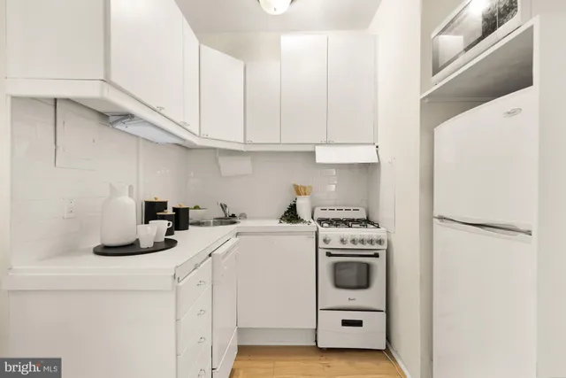 a kitchen with refrigerator a stove a sink and white cabinets