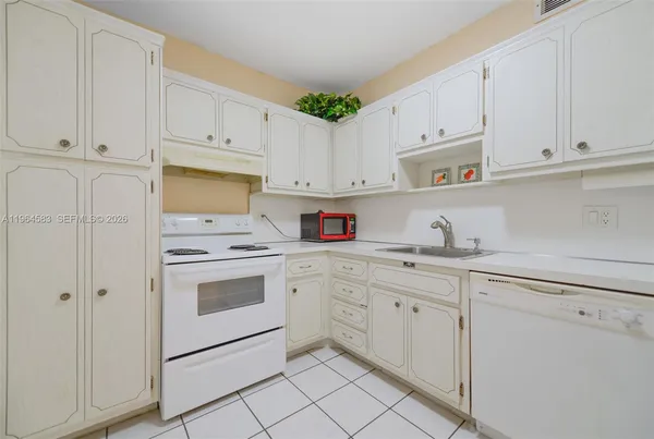 a kitchen with granite countertop white cabinets and white appliances