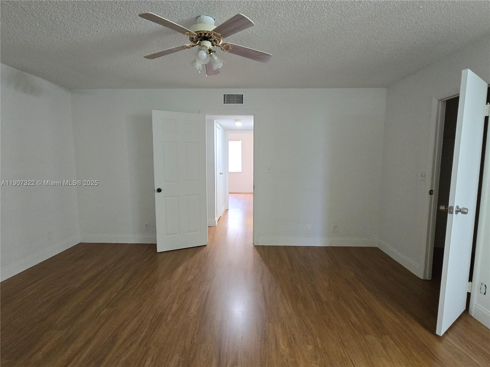 2650 Northwest 60th Way, Unit 176 Sunrise, FL 33313 - Photo 16 of 20 an empty room with wooden floor chandelier fan and windows