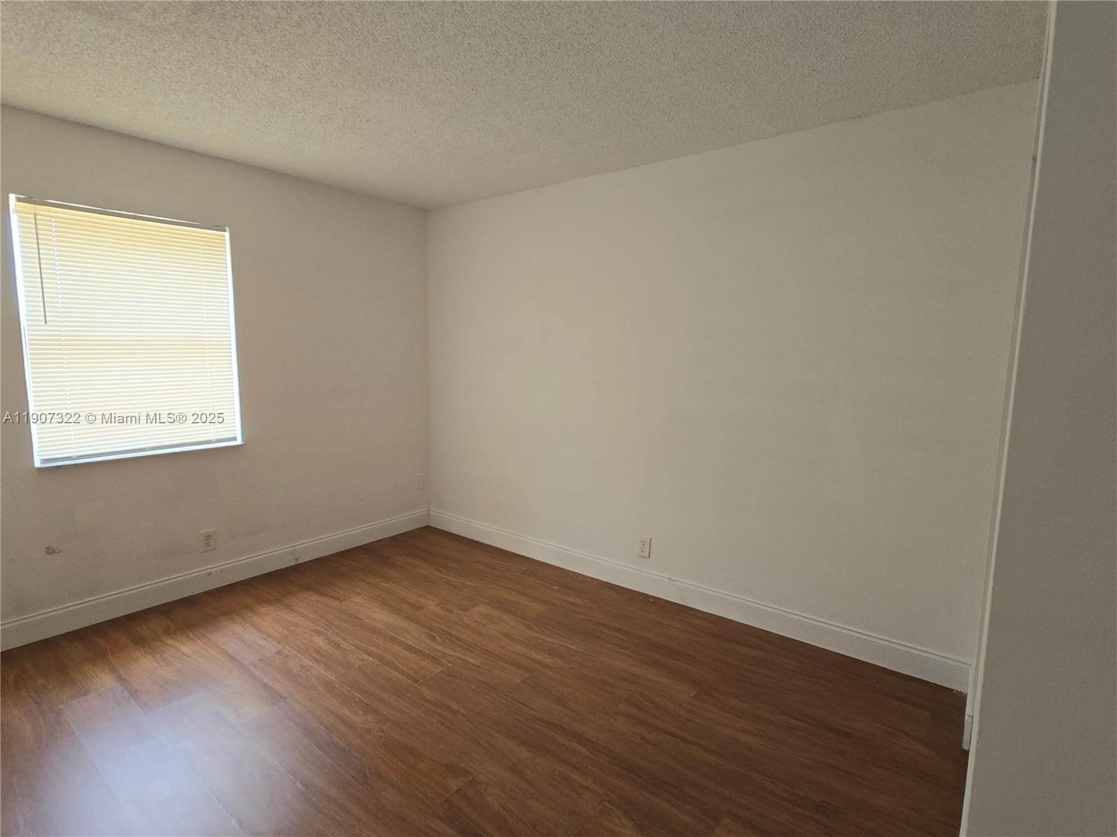 2650 Northwest 60th Way, Unit 176 Sunrise, FL 33313 - Photo 7 of 20 a view of an empty room with wooden floor and a window